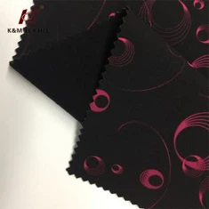 赤い円模様がプリントされた黒い底のソフトシェル生地